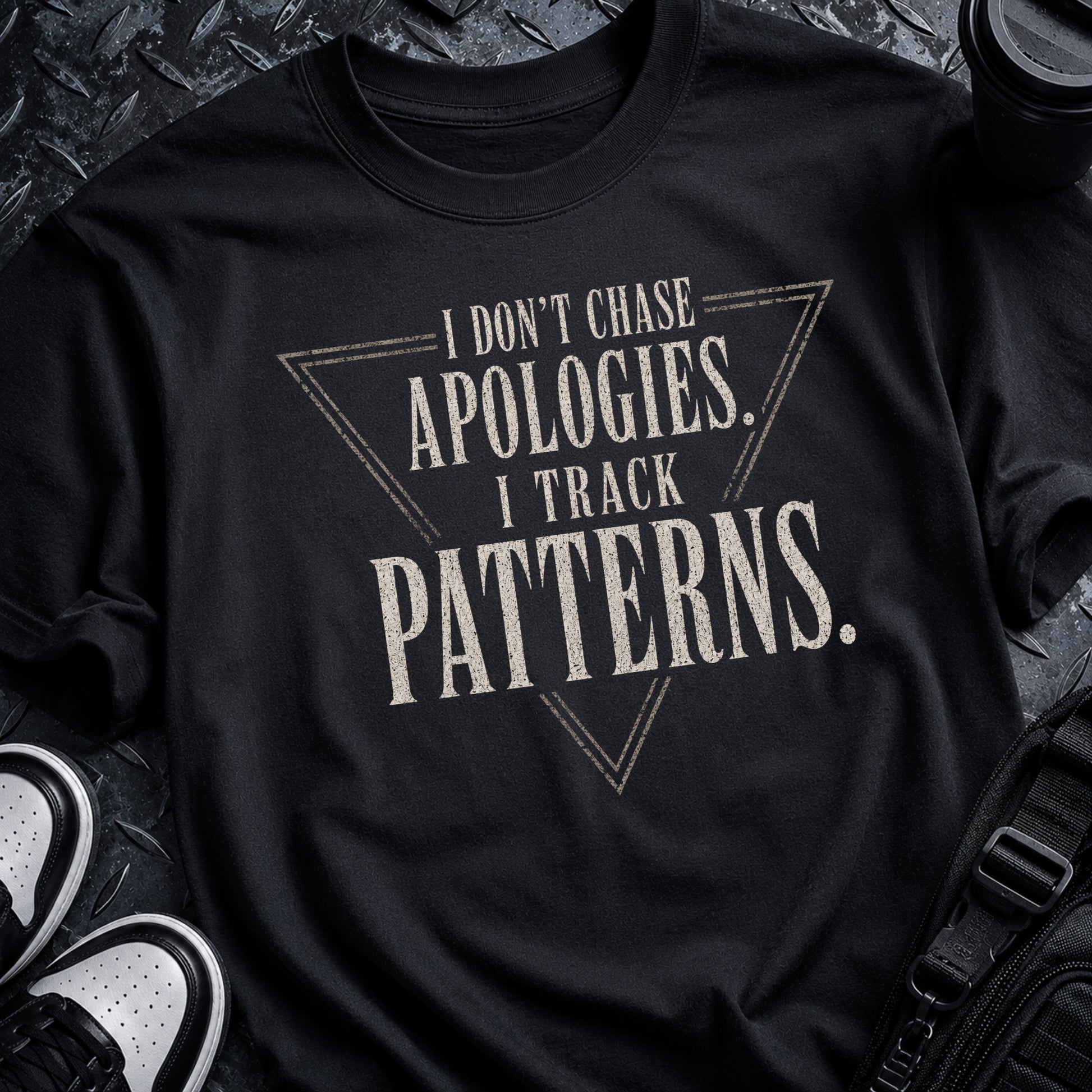 Black unisex T-shirt featuring the distressed quote I Don’t Chase Apologies. I Track Patterns.